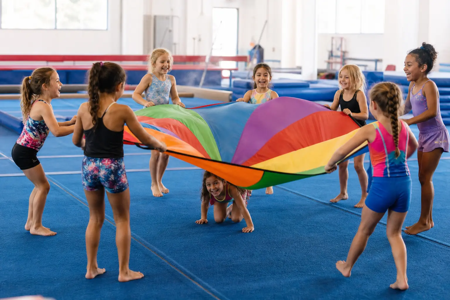 Children lifting a rainbow parachute in the gym